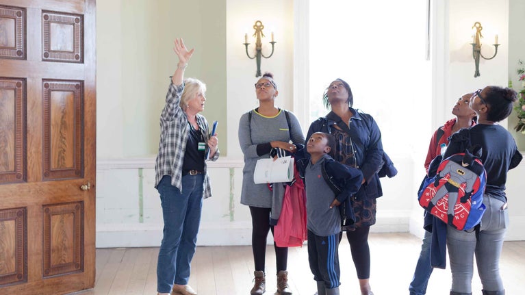 Volunteer room guide with visitors inside the house at Croome, Worcestershire